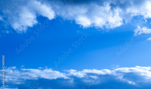 Blue sky with clouds on the top and the bottom of the composition and free space in the centre.