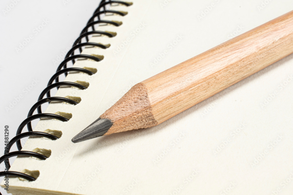 Single wooden pencil lying in the blank diary page, macro shot with selective focus Single wooden pencil lying in the blank diary page, macro shot with selective focus