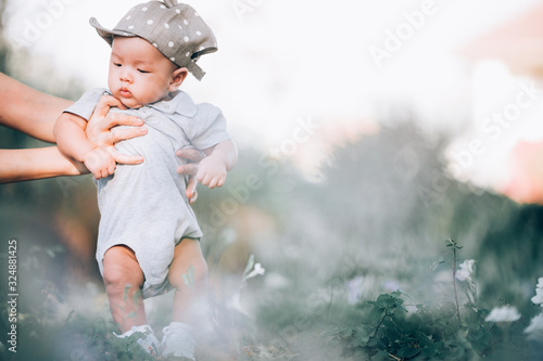 Fototapeta Naklejka Na Ścianę i Meble -  Portrait of a asian  3 months old baby boy on green grass outdoor in  park.