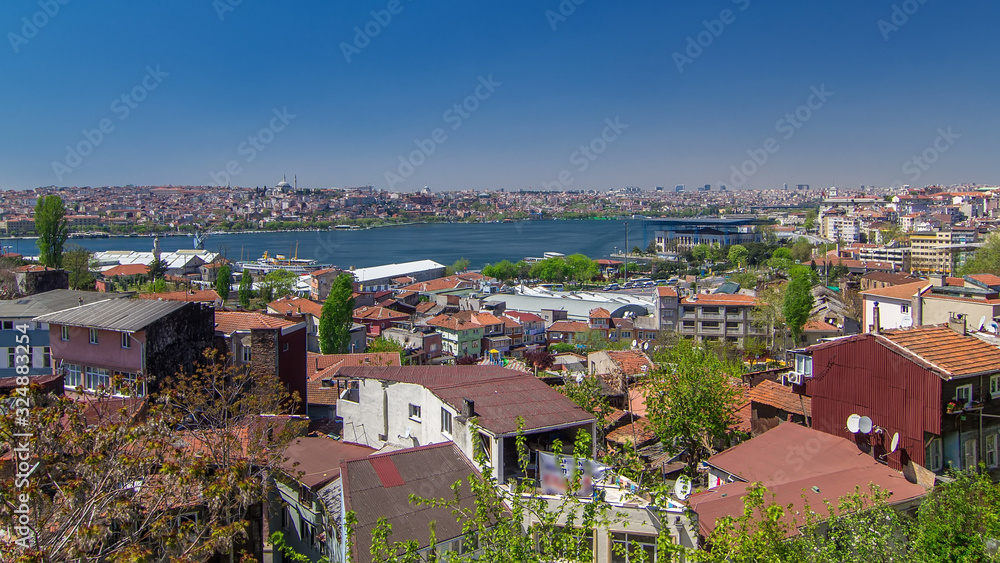 Panoramic top view with red roofs of houses and mosques behind Golden Horn timelapse in Istanbul, Turkey.