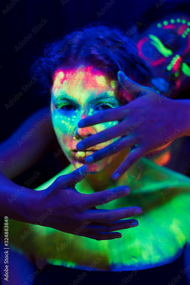 Woman with fluorescent make-up with hands on her face Woman with fluorescent make-up with hands on her face