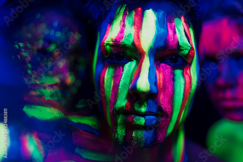 Close-up view of man with colorful fluorescent make-up