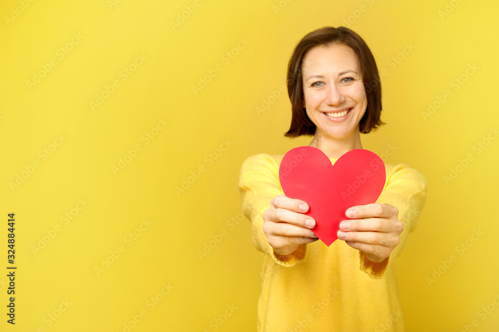 Beautiful woman holding heart on yellow background Beautiful woman holding heart on yellow background