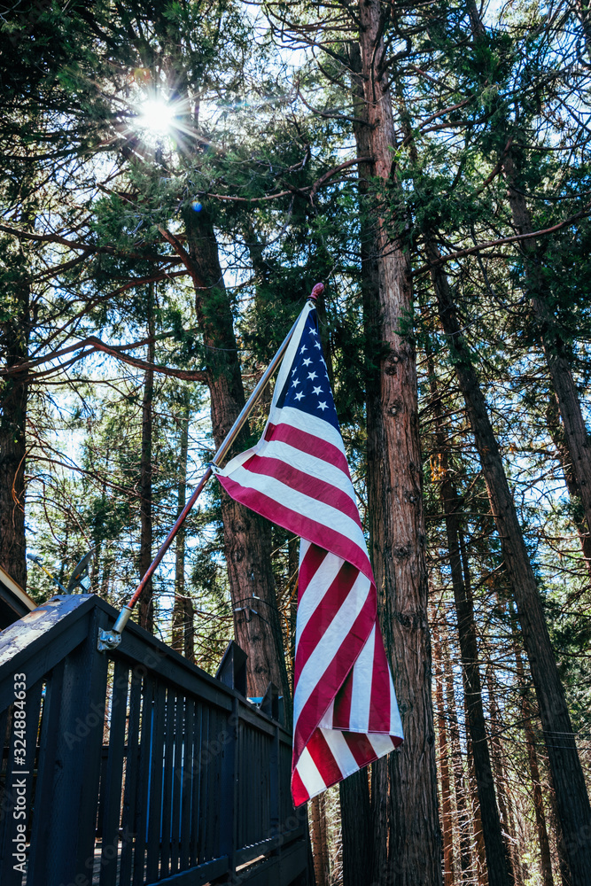 American flag hung on the porch of a wooden cottage in the forest. American patriotism