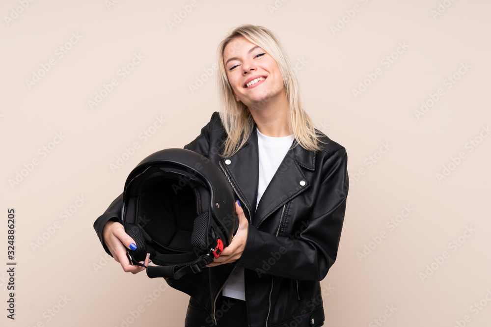 Young blonde woman with a motorcycle helmet over isolated background with happy expression Young blonde woman with a motorcycle helmet over isolated background with happy expression