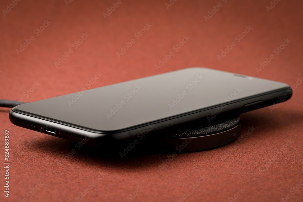 The smartphone is charged by a wireless charger Concept of new technologies. The smartphone is charged by a wireless charger Concept of new technologies.