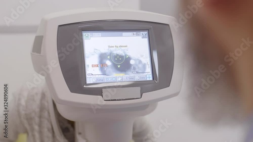 Over the shoulder shot of professional optometrist looking at autorefractor screen displaying eye of little boy during vision test in ophthalmology clinic photo