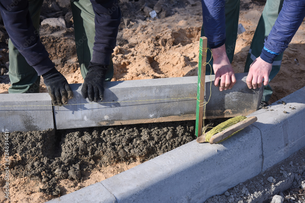 Builders install a road curb in cement. Builders install a road curb in cement.