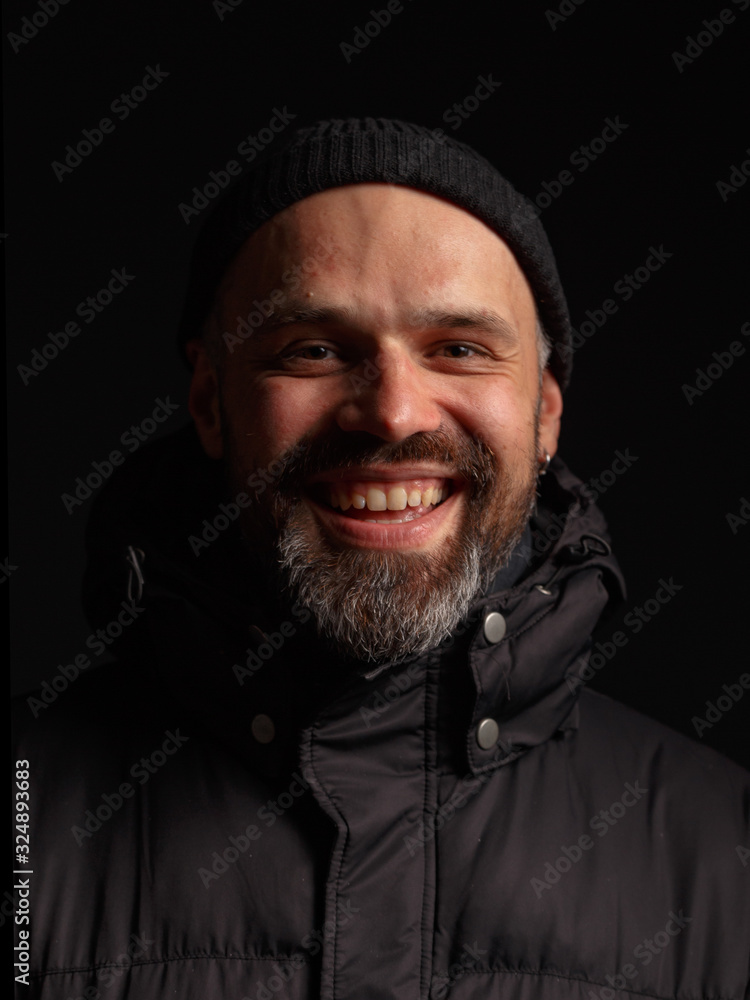 Portrait of a man in a hooded jacket. Studio shooting, dark background. Portrait of a man in a hooded jacket. Studio shooting, dark background.