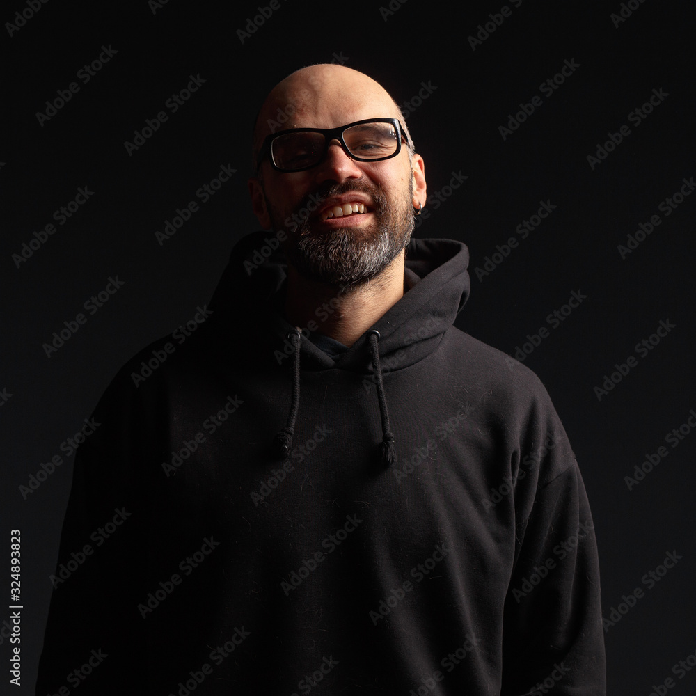 Obraz premium Portrait of a man in a hooded jacket. Studio shooting, dark background.