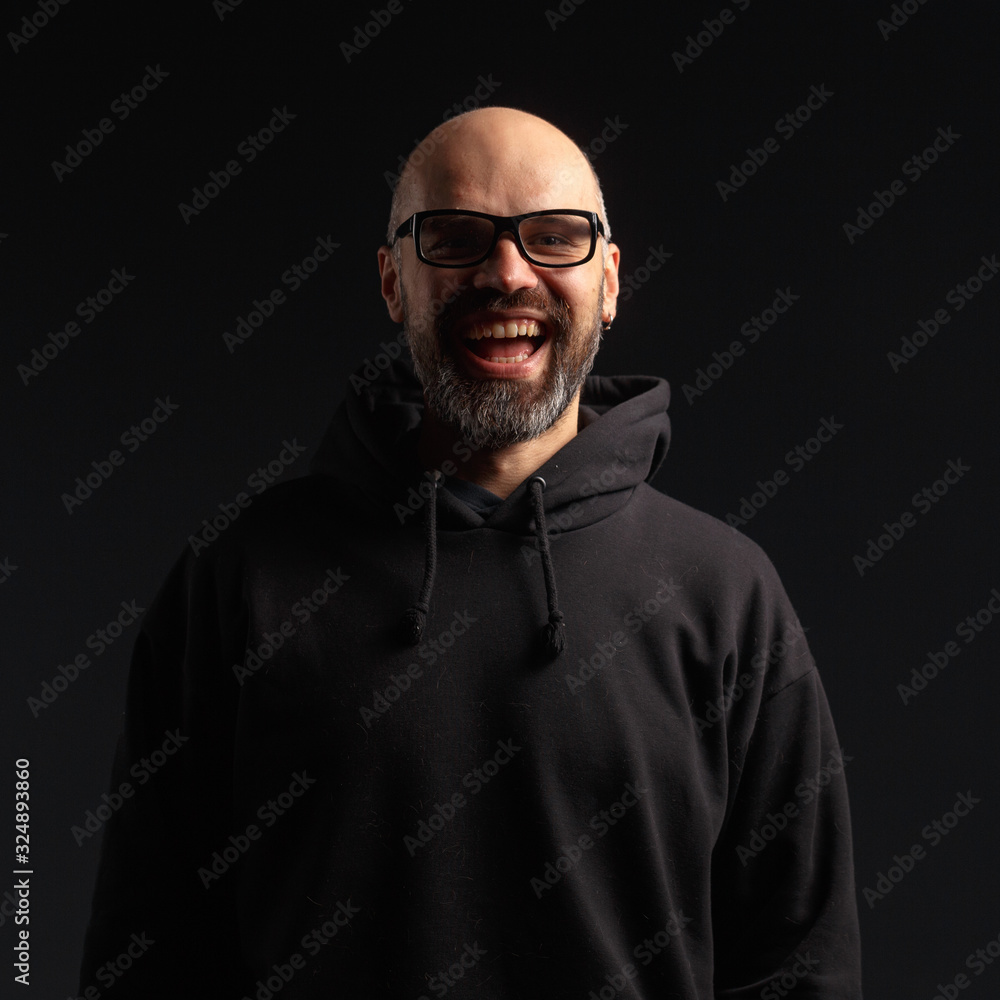 Obraz premium Portrait of a man in a hooded jacket. Studio shooting, dark background.