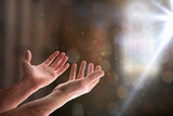 Hands with palms up in church with ray of light