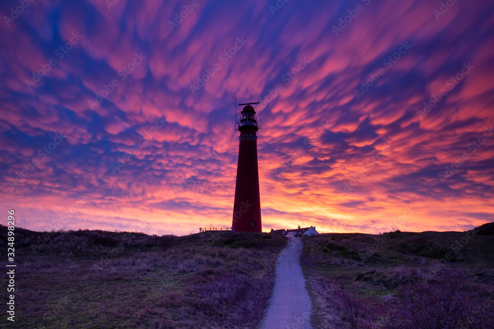 dramatic purple mammatus clouds over red lighthouse