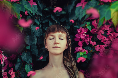 Portrait of a beautiful girl with African pigtails on a background of spring flowers. outdoor fashion photos. Spring blossom