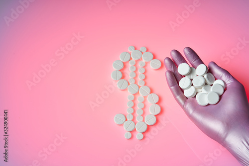 White pills are in the form of a dollar sign on a pink background, many white pills are in the palm of your hand. Healthcare is a profitable business.