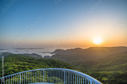 Landscape view of sunset from Mount Inasa Observation platform with banister of tower in foreground (Nagasaki, Japan) photo