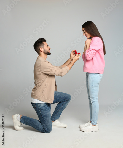 Canvas Print Man with engagement ring making marriage proposal to girlfriend on light grey ba