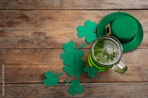 Green beer, hat and clover leaves on wooden table, flat lay with space for text. St. Patrick's Day celebration