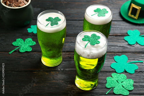 Green beer and clover leaves on black wooden table. St. Patrick's Day celebration
