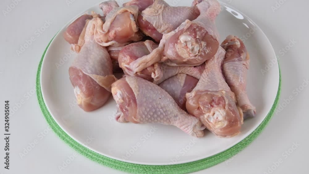 Laying Raw Chicken Legs On A White Plate Laying Raw Chicken Legs On A White Plate