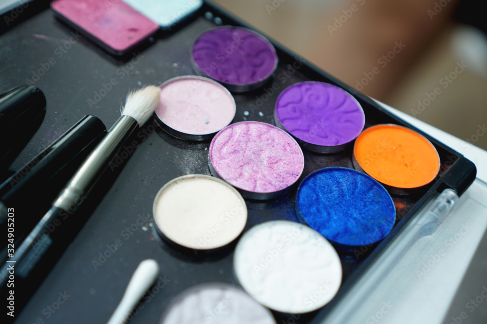 Naklejka premium Use palette of shadows for makeup on a blurred background, closeup