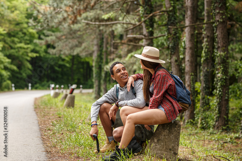Two  friends hiking in nature.They sitting and resting by the old country road.  © BalanceFormCreative