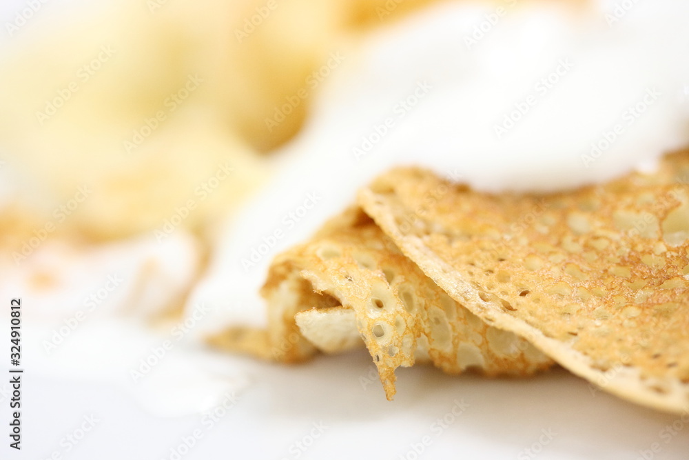 A pancake with a golden crust poured sour cream