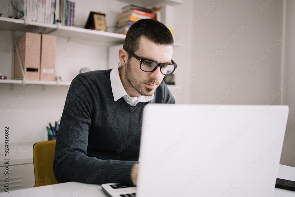 Young businessman sitting at desk and using laptop Young businessman sitting at desk and using laptop
