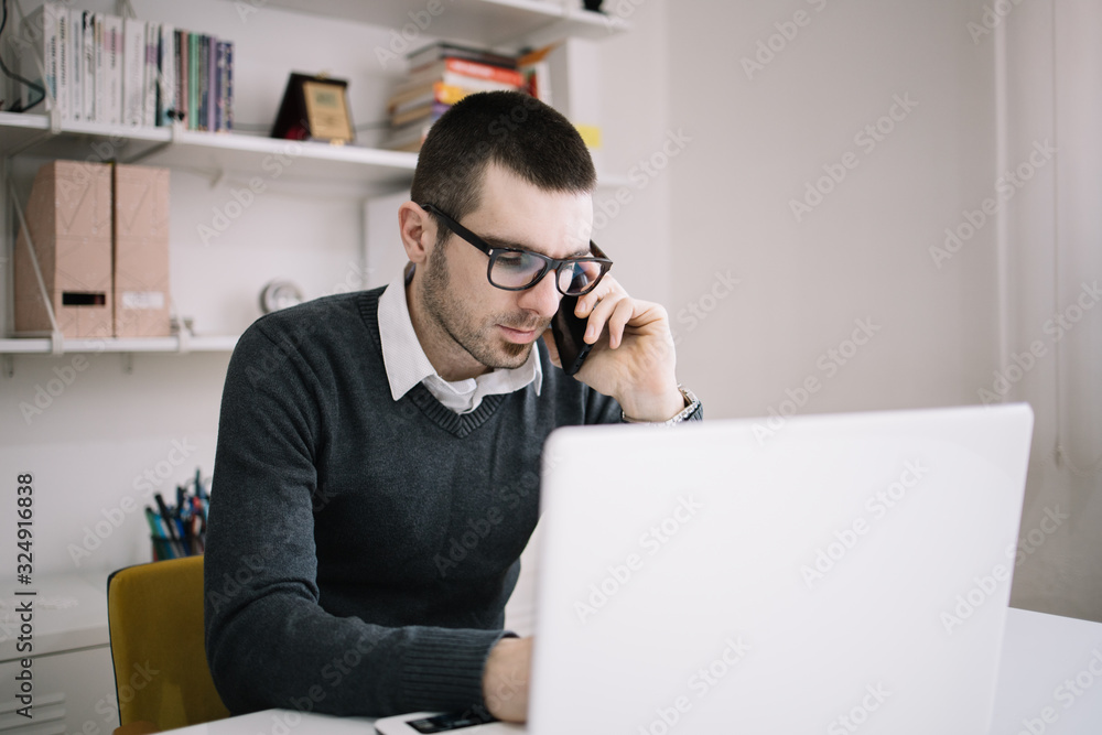 Broker talking on phone while working with laptop Broker talking on phone while working with laptop