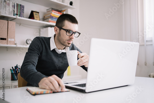 Employee holding white mug while using laptop