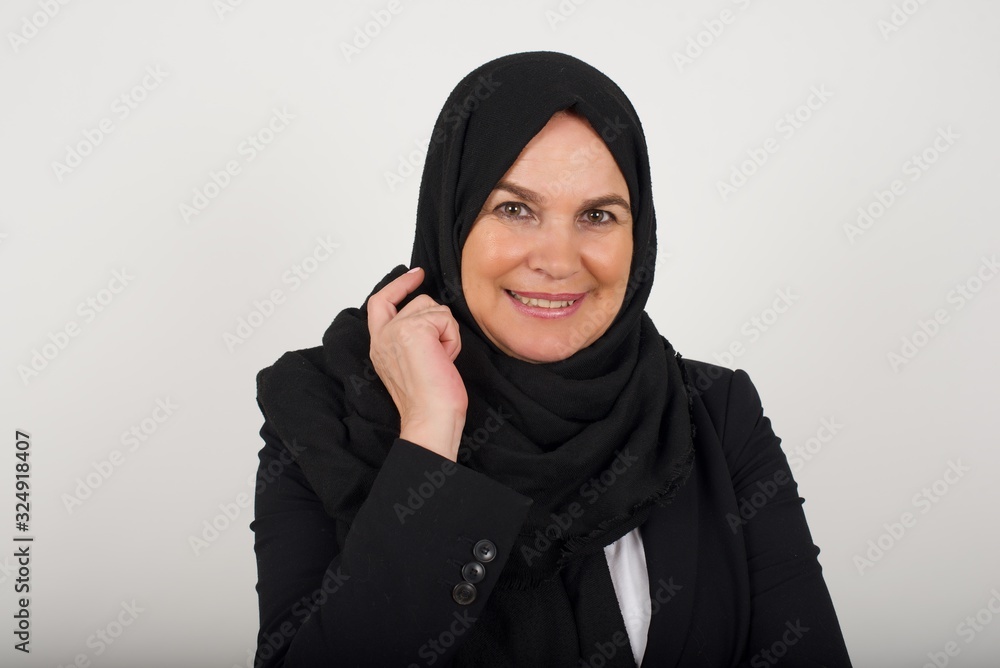 Image of cheerful pretty young caucasian lady standing against gray wall with hand near face. Looking with glad expression at the camera after listening to good news. Confident girl. Image of cheerful pretty young caucasian lady standing against gray wall with hand near face. Looking with glad expression at the camera after listening to good news. Confident girl.