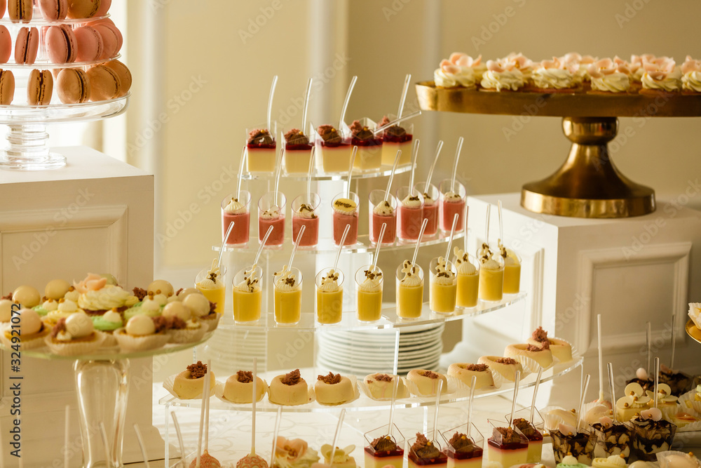 Delicious desserts for a party. Cupcakes, gelatin desserts, macaron cakes on tray. Pink, white and chocolate party cakes Delicious desserts for a party. Cupcakes, gelatin desserts, macaron cakes on tray. Pink, white and chocolate party cakes