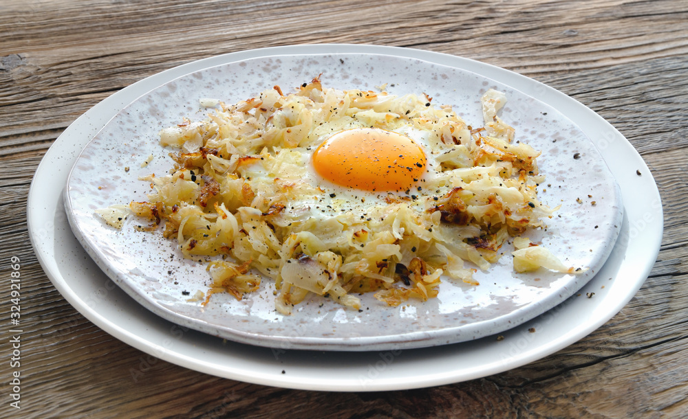 egg and fried cabbage on fleck ceramic plate on wooden background egg and fried cabbage on fleck ceramic plate on wooden background