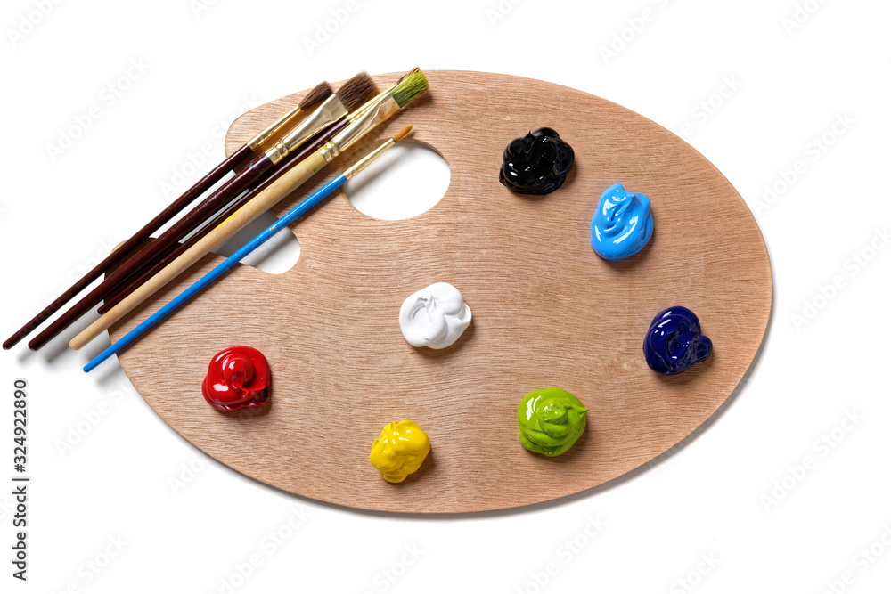 A wooden artists palette with bright colored paint and brushes A wooden artists palette with bright colored paint and brushes