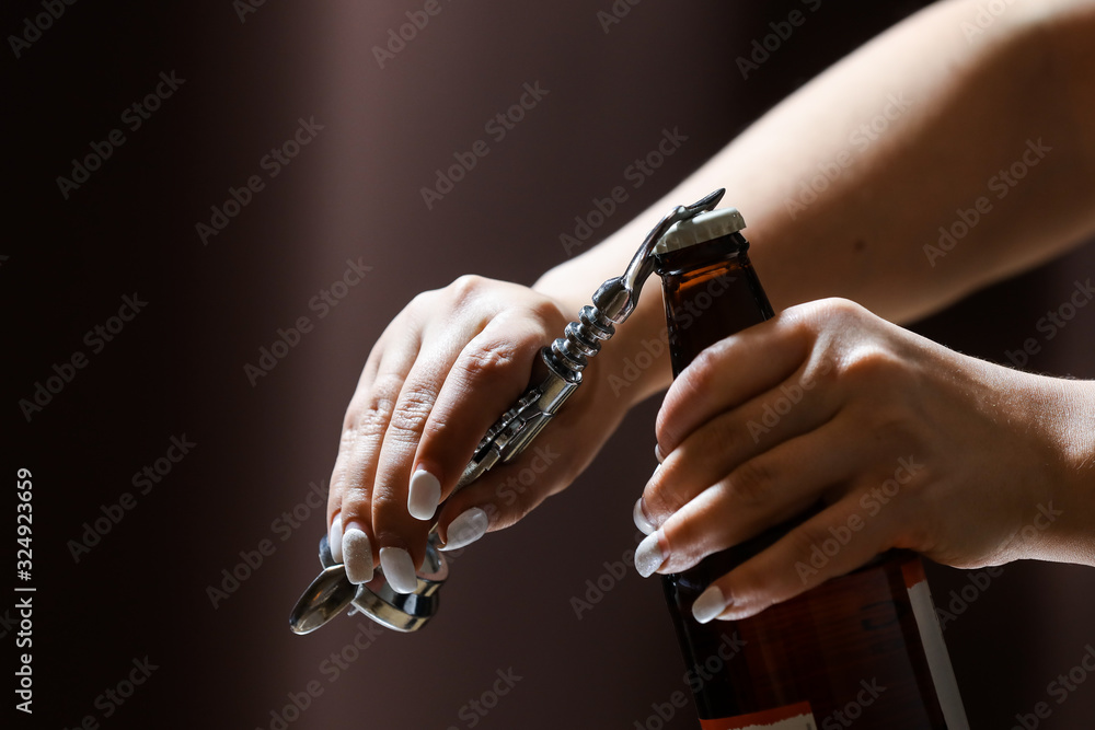 Girl with white nails opens and pours a glass of cider/beer from the bottle.