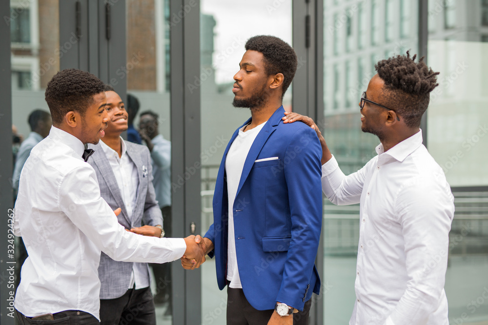 team of young african men near the building shake hands team of young african men near the building shake hands