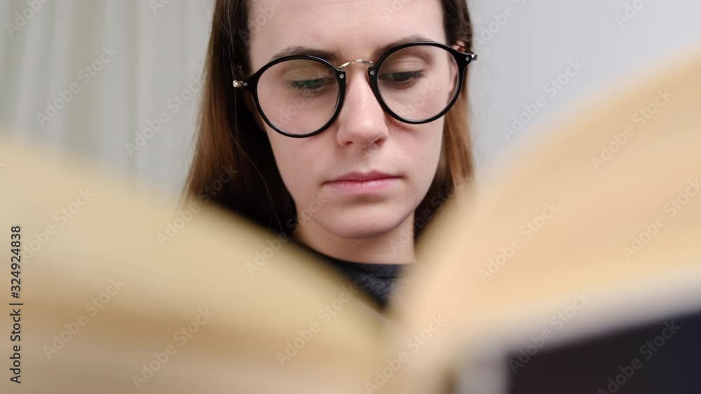 Attractive girl in eyeglasses reading interesting bestseller paper book novel. Peaceful woman enjoying hobby leisure free time alone at home. Attractive girl in eyeglasses reading interesting bestseller paper book novel. Peaceful woman enjoying hobby leisure free time alone at home.