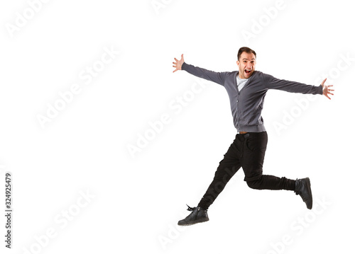 Excited young man jumping and smiling isolated