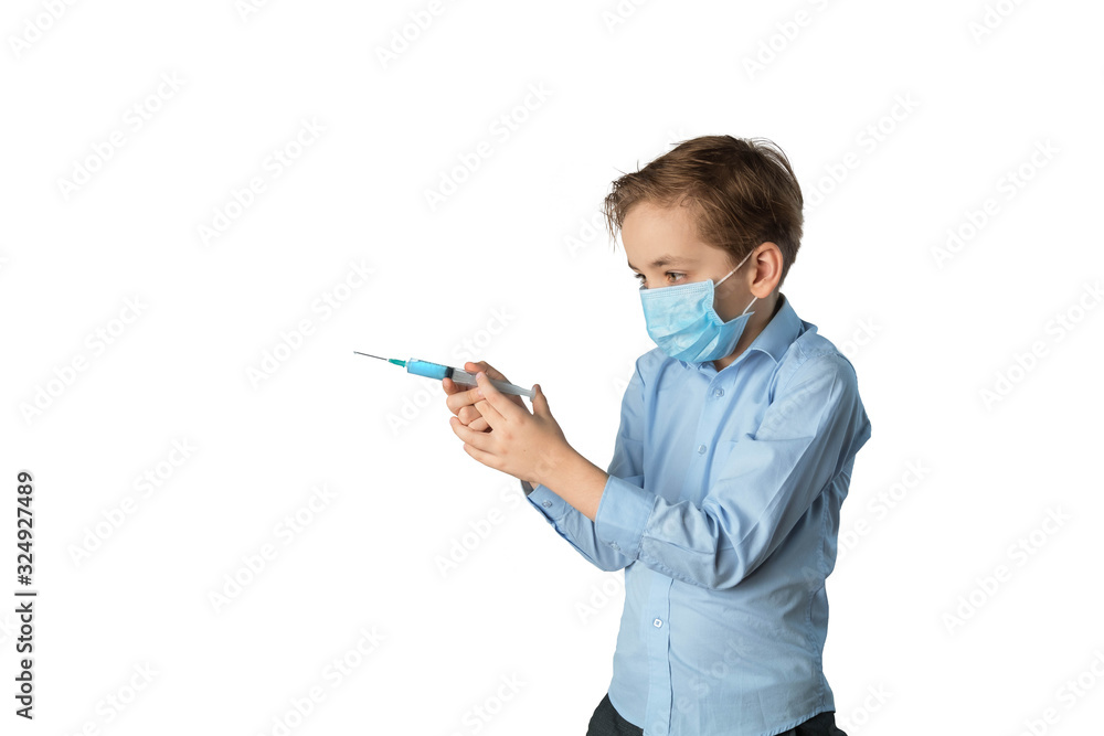 Caucasian boy holds a syringe with the vaccine as a gun. A boy wearing a medical mask, a blue shirt. White isolated background, place for inscription Caucasian boy holds a syringe with the vaccine as a gun. A boy wearing a medical mask, a blue shirt. White isolated background, place for inscription