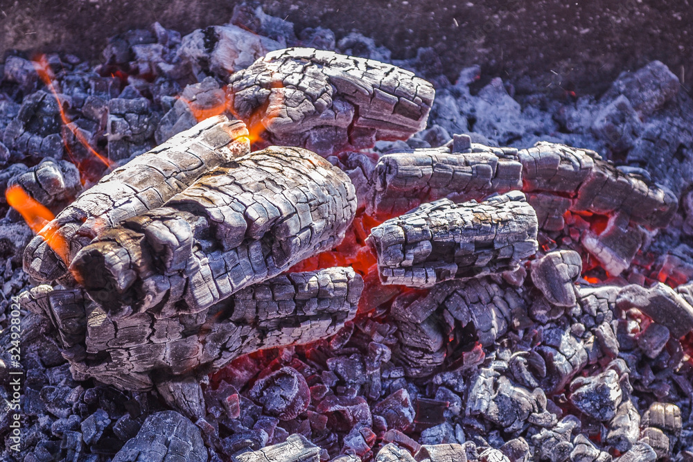 Smoldering ashes of a bonfire. Incandescent orange and red embers texture. Dark background. Fire flame and Firewood in a brick barbecue. A place for cooking meal outside. smouldering embers on a surfa Smoldering ashes of a bonfire. Incandescent orange and red embers texture. Dark background. Fire flame and Firewood in a brick barbecue. A place for cooking meal outside. smouldering embers on a surfa