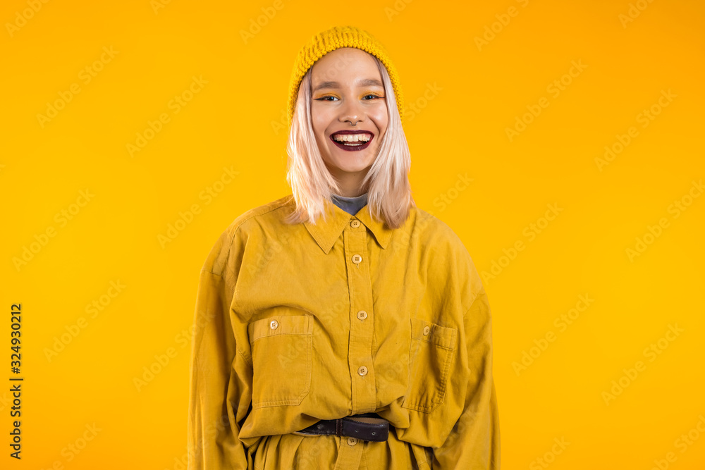 Young woman in total trendy yellow look. Portrait of beautiful punk girl with dark make-up and nose piercing on studio background. Young woman in total trendy yellow look. Portrait of beautiful punk girl with dark make-up and nose piercing on studio background.