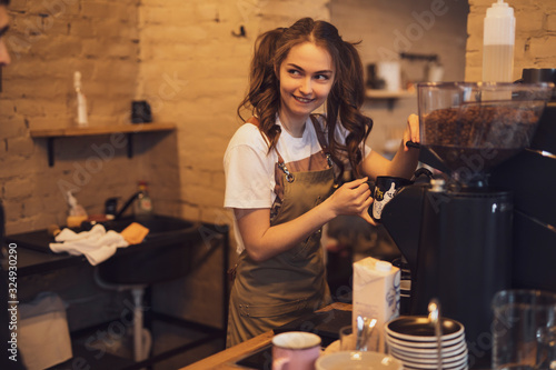 Young and cheerful barista woman make a coffee in the cafeteria