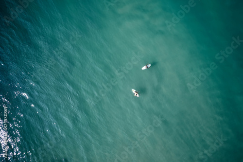 Aerial view of two men on a surfboard in the turquoise waters in Kerala, India