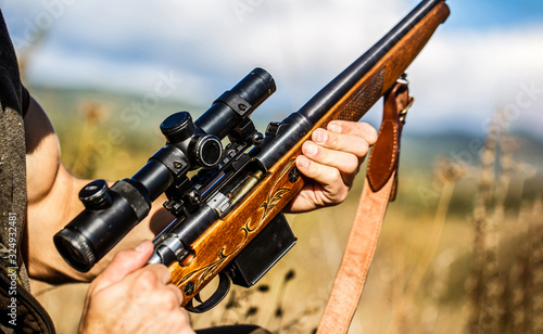 Male with a gun, rifle. Process of hunting during hunting season. Male hunter in ready to hunt. Closeup. The man is on the hunt, sport. Hunter man. Hunting period. Man is charging a hunting rifle