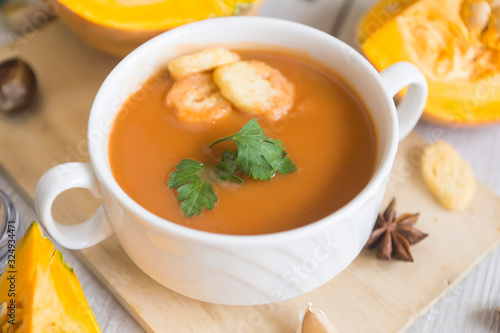 umpkin puree soup, pumpkin, spices on a wooden white background.