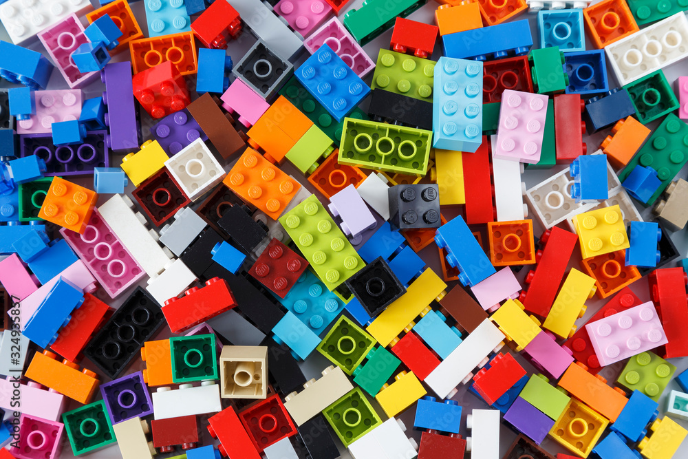 Fototapeta premium Close-up of a cluttered pile of colorful Lego bricks viewed from above. Top view.