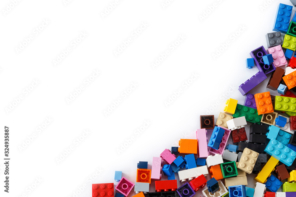 Naklejka premium Close-up of a cluttered pile of colorful Lego bricks viewed from above with place for content or text. Isolated on white background, top view. Copy space.