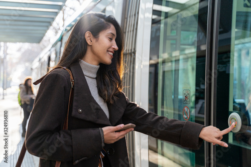 Smiling young woman pushing the button at a tram photo