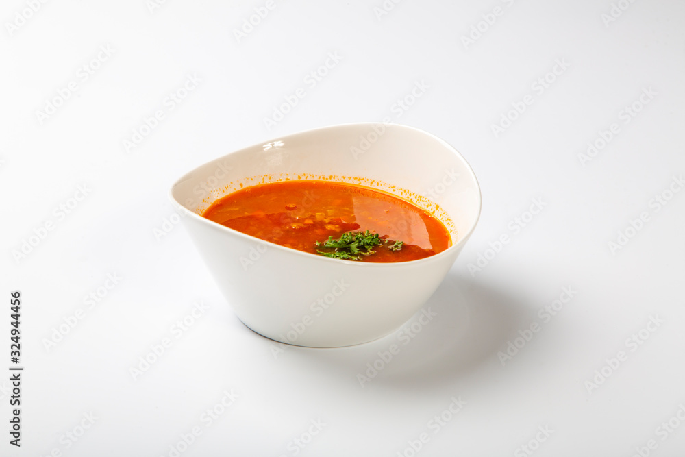 Beef goulash soup with tongue. A white oval plate with red soup stands on a white background. Beef goulash soup with tongue. A white oval plate with red soup stands on a white background.