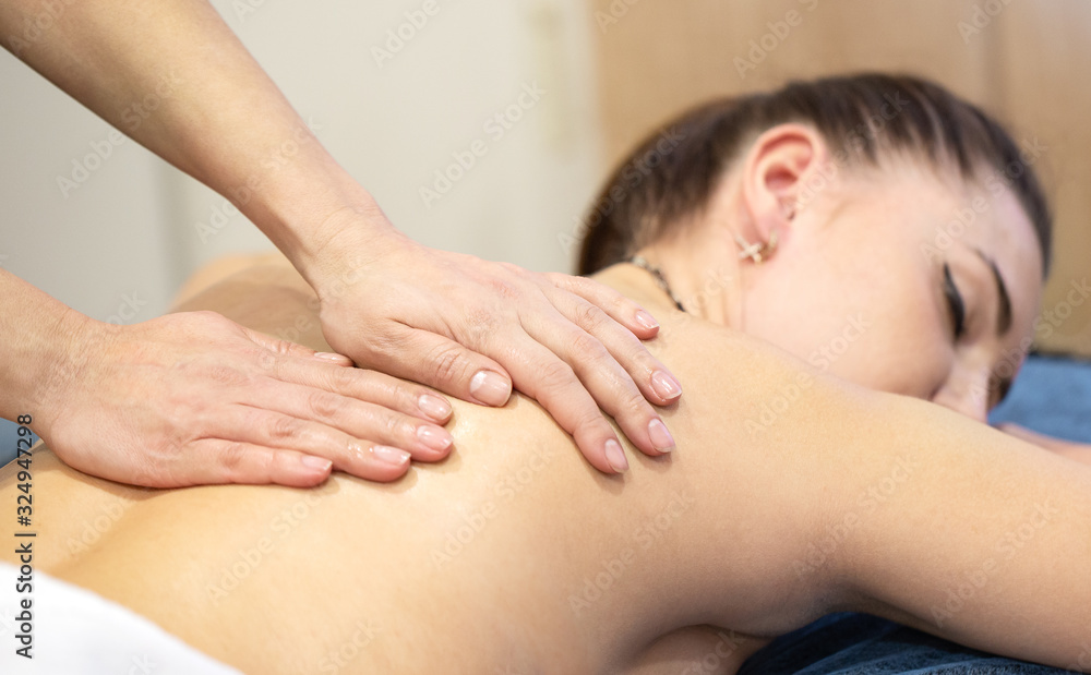 Hands of a masseur woman on the back of a young girl Hands of a masseur woman on the back of a young girl